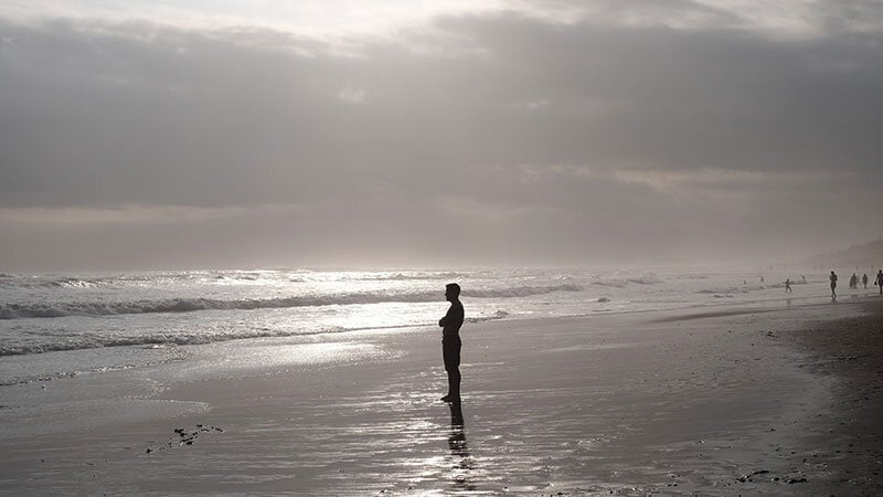 person standing on beach looking out at ocean, black and white photo