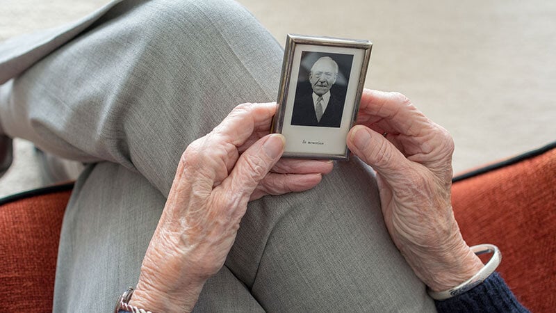 older woman's hands holding photo of deceased husband