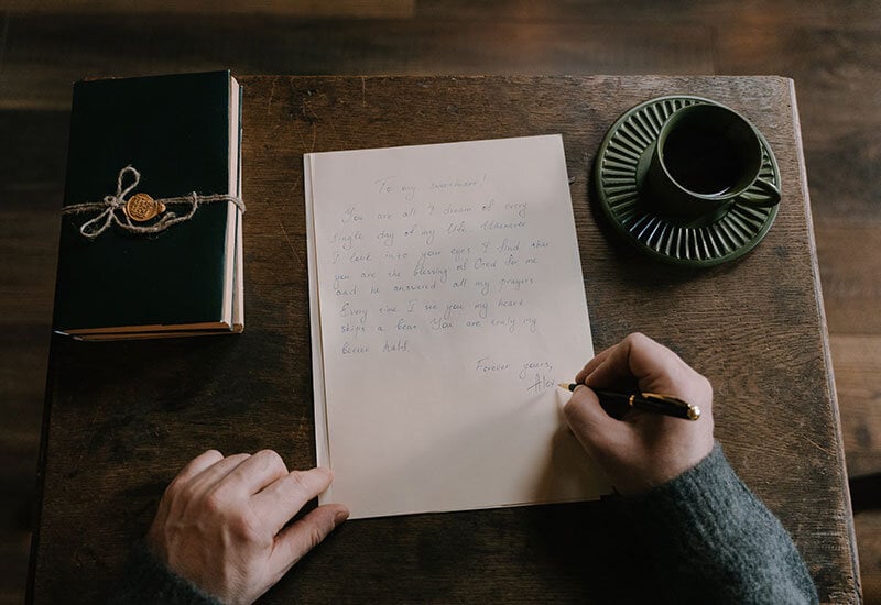 someone hand writing a memorial letter to a deceased loved one