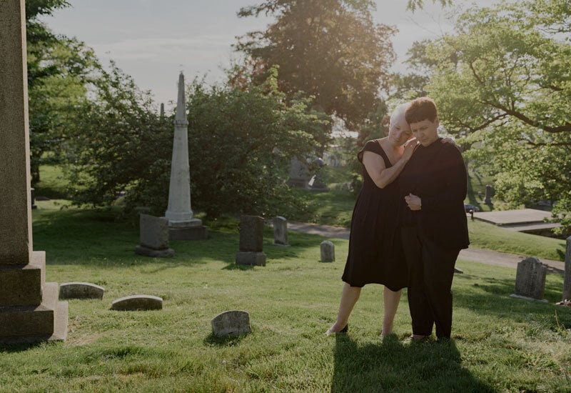 2 women mourning deceased loved on at cemetery