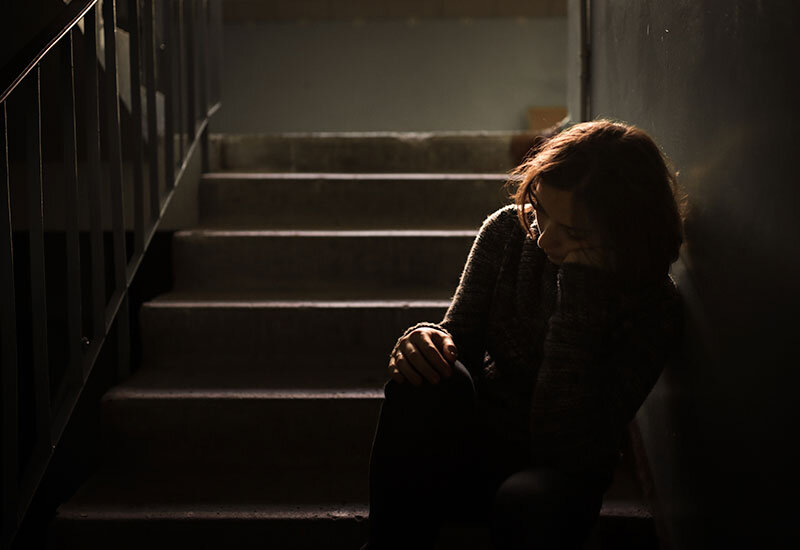 young woman grieving alone in a dark stairway near downtown los angeles