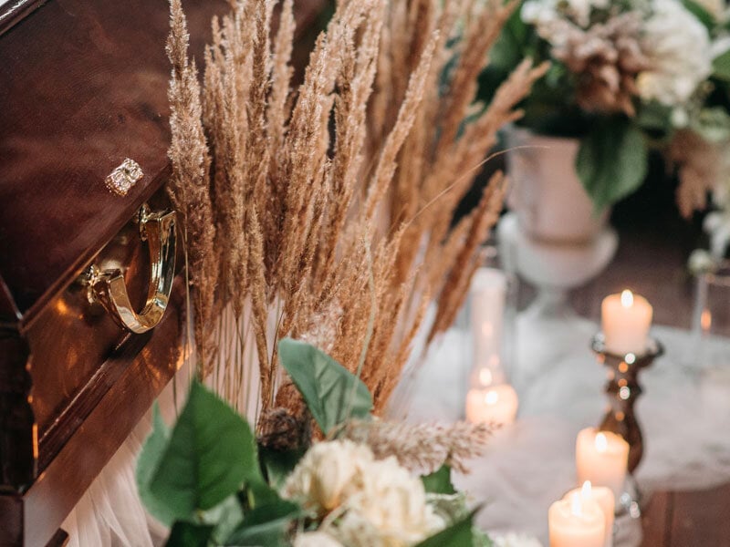 wooden funeral casket with flowers and candles