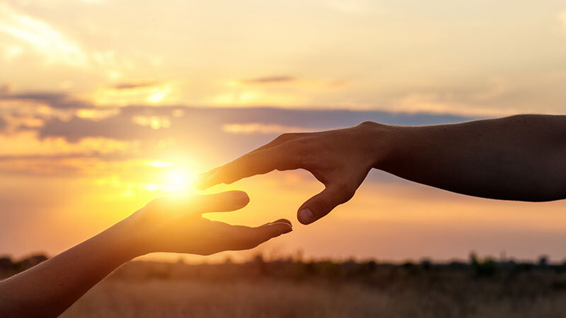 2 hands reaching to touch with sunset over landscape near hollywood CA