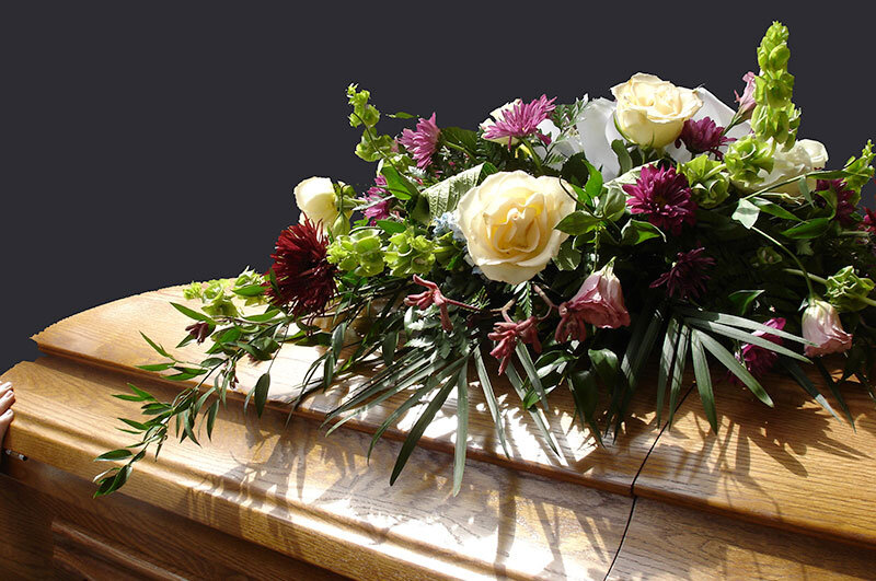 oak wood funeral casket with loral arrangement in New City Church in LA