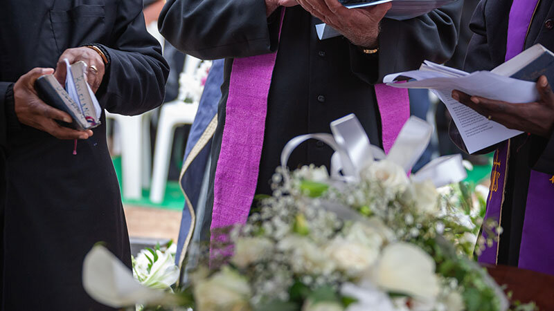 3 african american priests reading scriptures at a funeral near los angeles