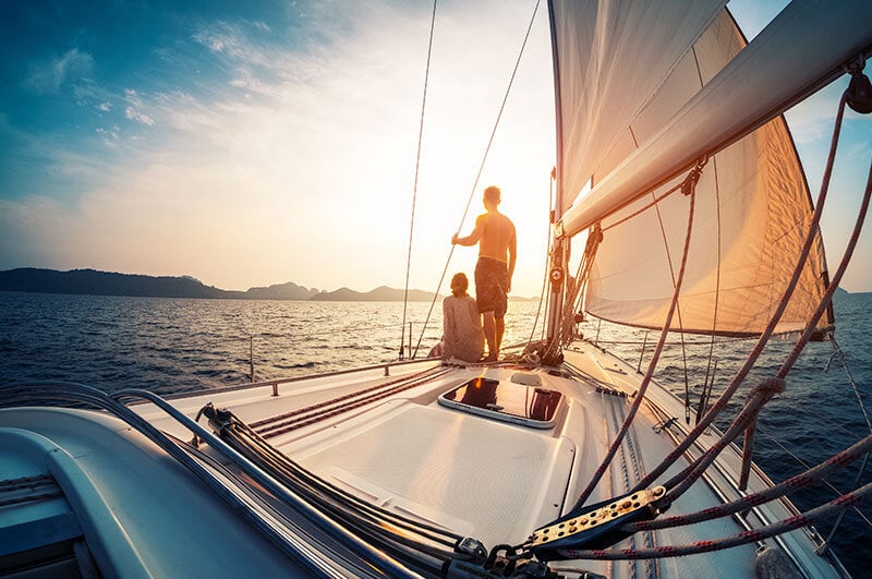 2 people standing on boat's bow while at sea scattering ashes