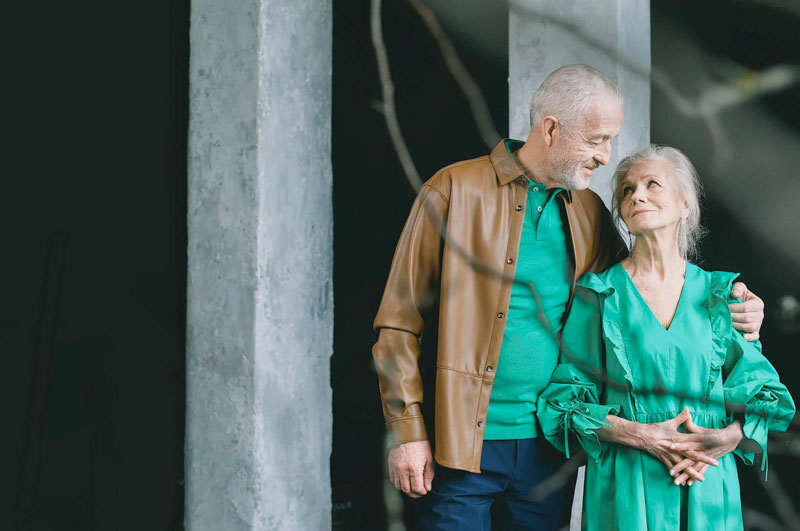 older couple standing close and smiling at each other outside of Santa Monica Courthouse