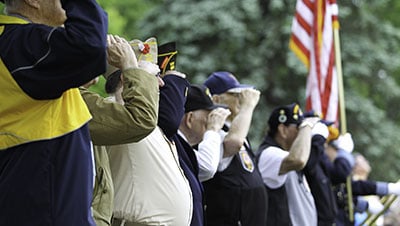 older veterans at cemetery soluting American flag
