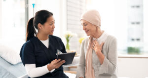 Tablet, nurse and woman with cancer patient, elderly and hospital consultation for wellness. Tech, happy and medical professional with sick senior person coughing for advice, healthcare or support.