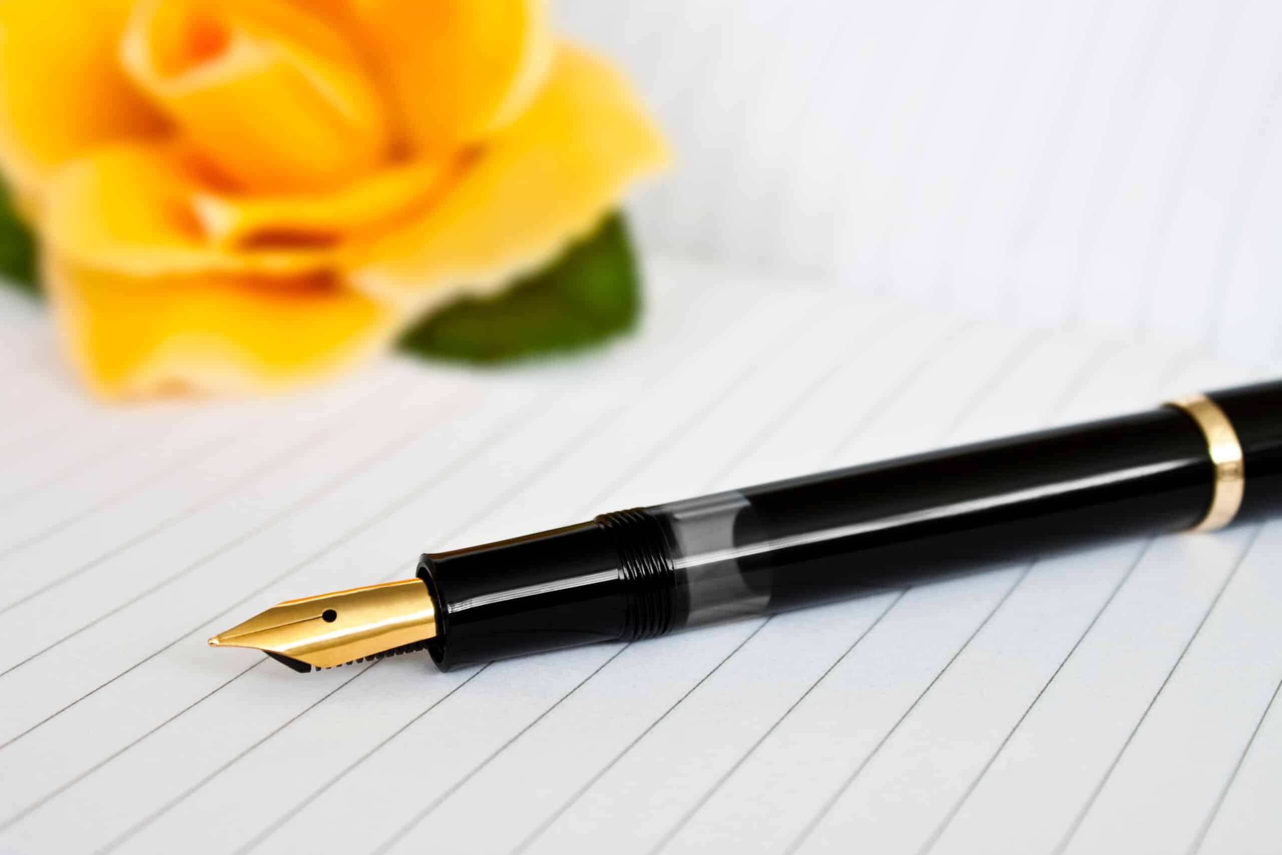 A flower, pen, and paper, signifying how to write an obituary